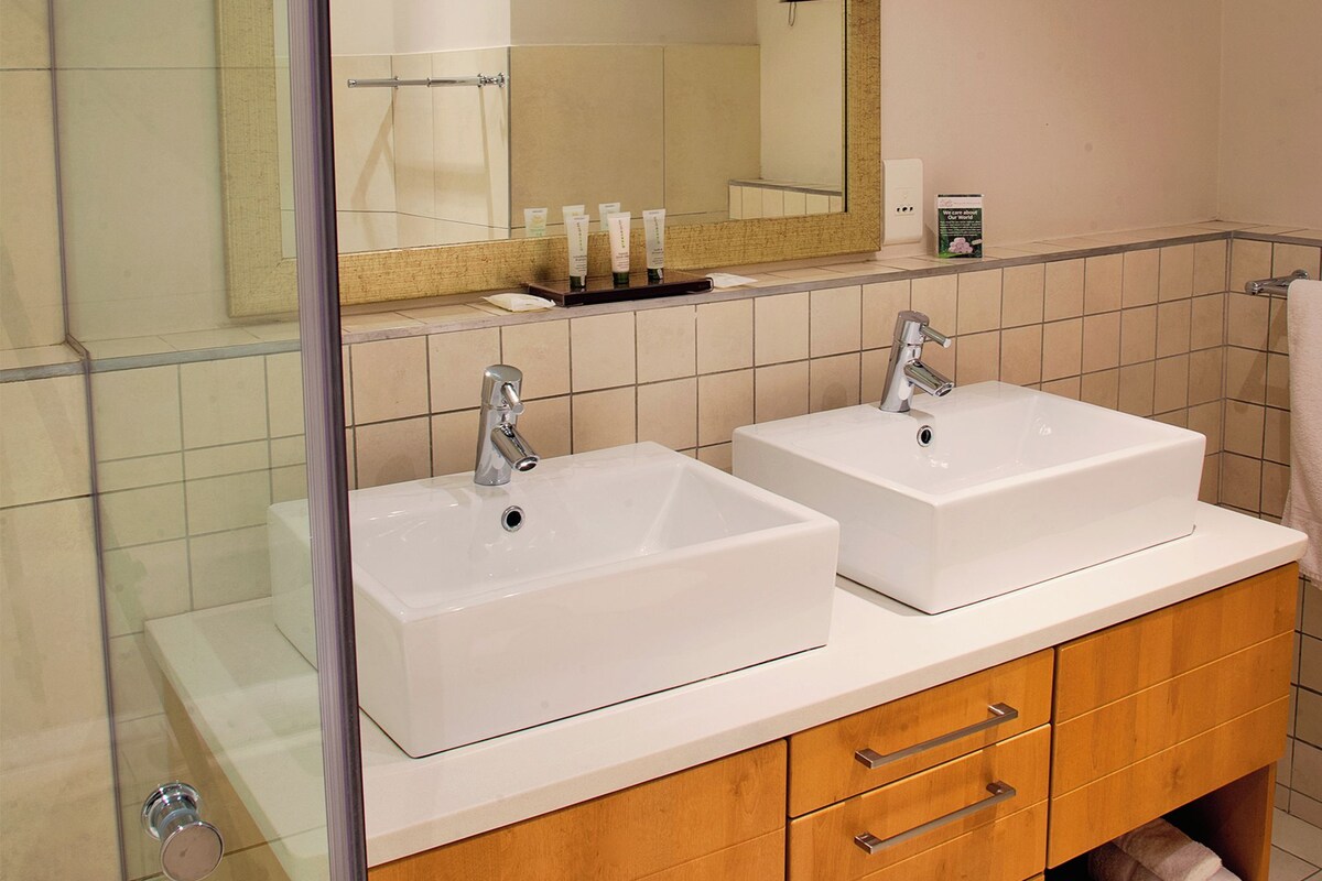 A bathroom with two white sinks, a mirror, and a wooden vanity with drawers.
