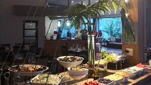 A buffet setup with various food items and a large potted plant. - Premier Resort The Moorings, Knysna (Knysna)
