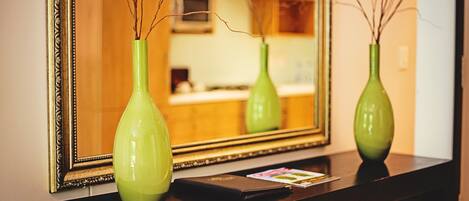 A mirror reflecting two green vases on a dark wooden dresser.