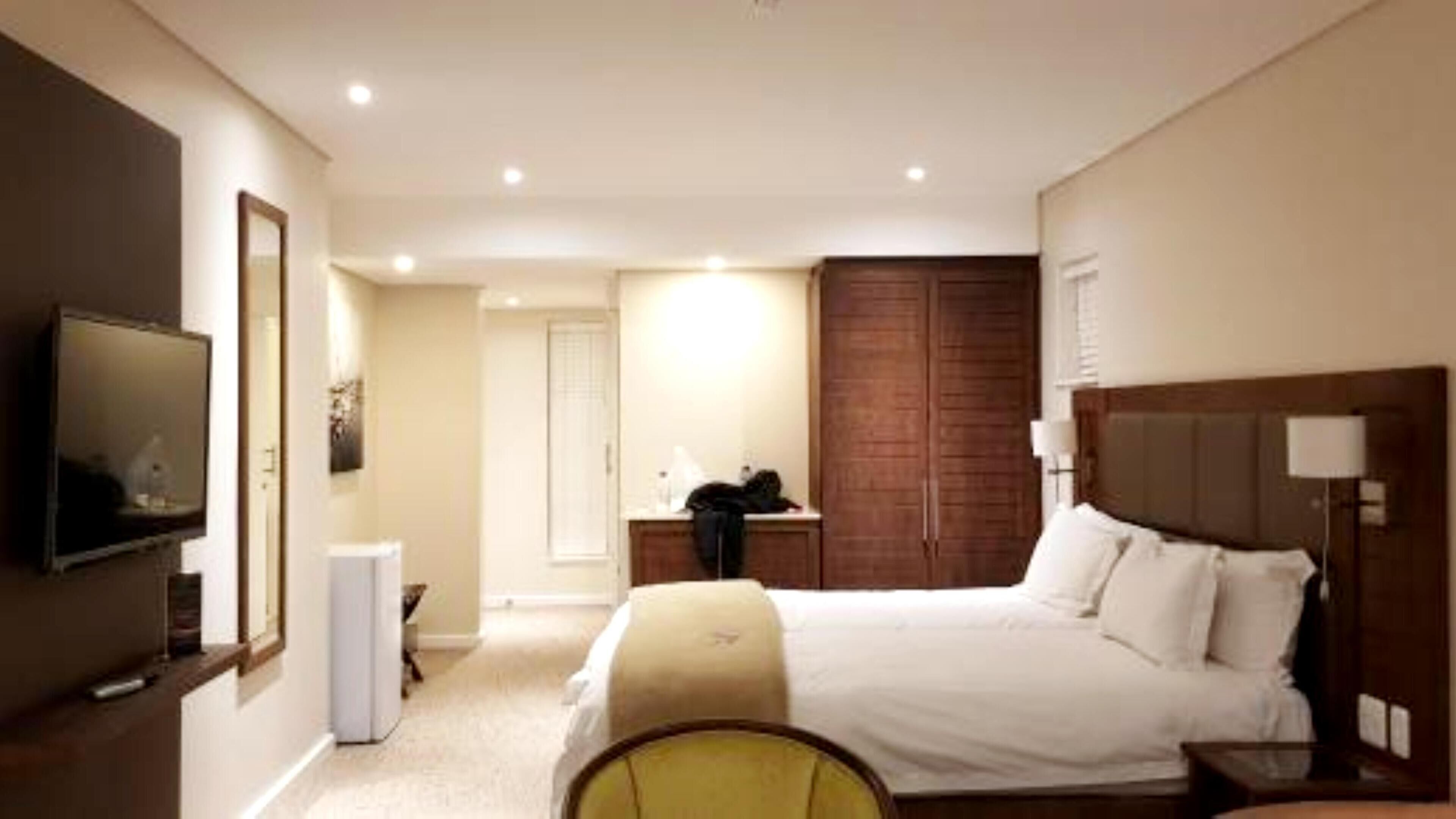 Een hotelkamer met een bed, een bureau, een stoel, een televisie en een kledingkast.