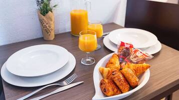 A breakfast setting with croissants, orange juice, and a small plant.