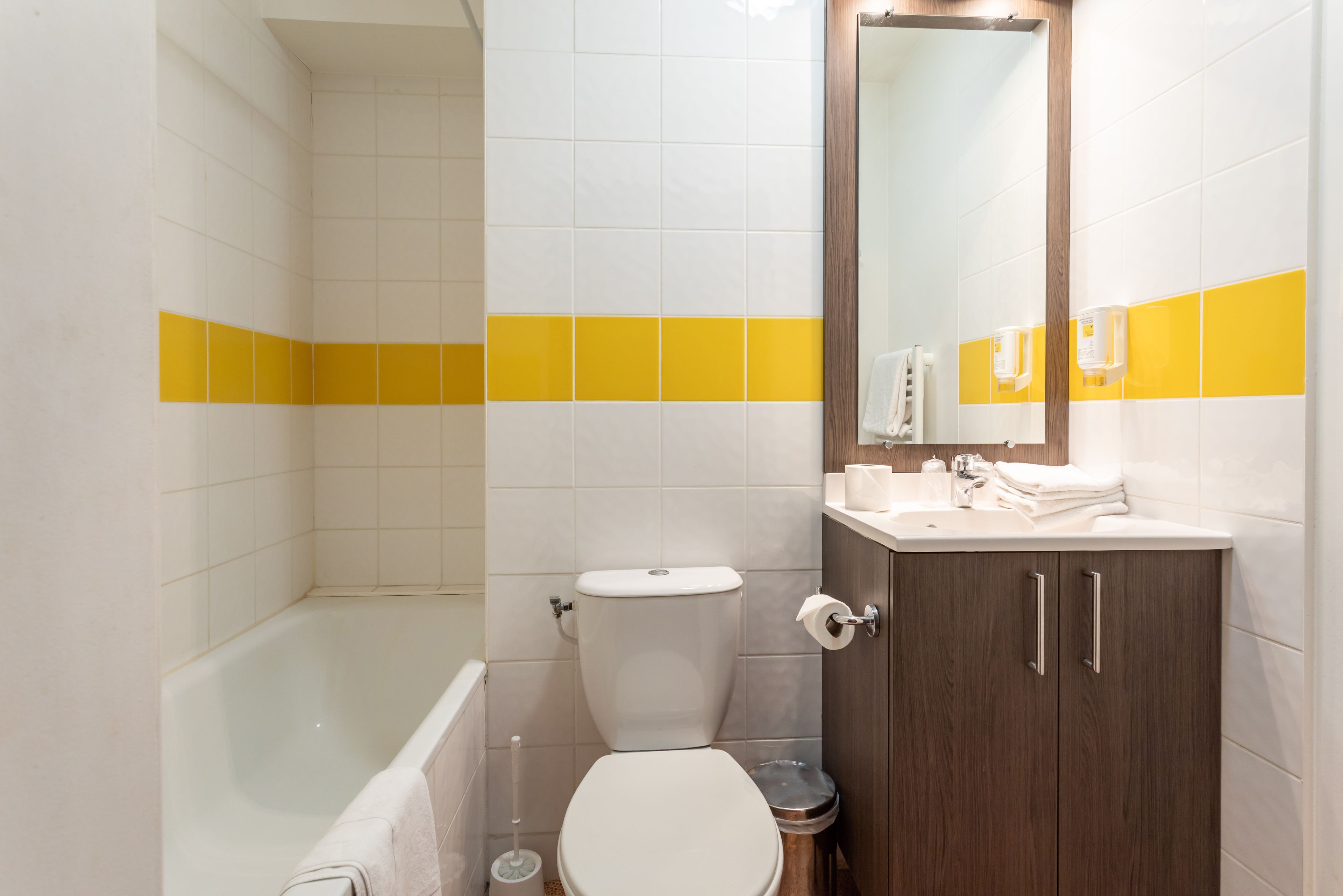 A bathroom with a bathtub, toilet, and vanity with a mirror.