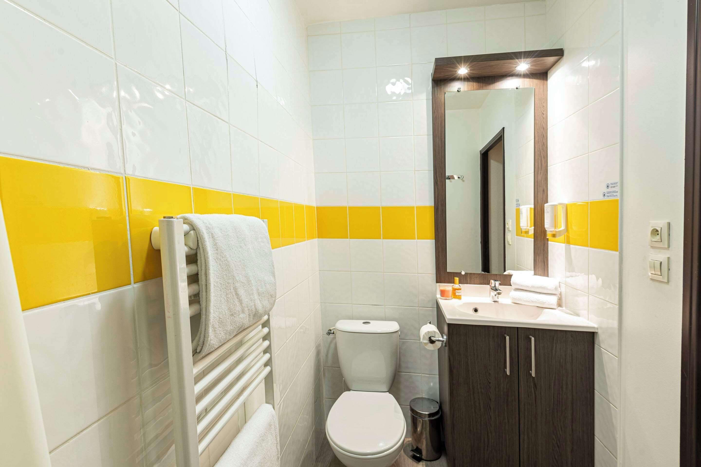 Een badkamer met toilet, wastafel en spiegel.