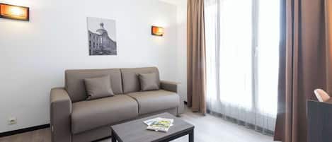 A modern living room with a sofa, a coffee table, and two wall-mounted lights.
