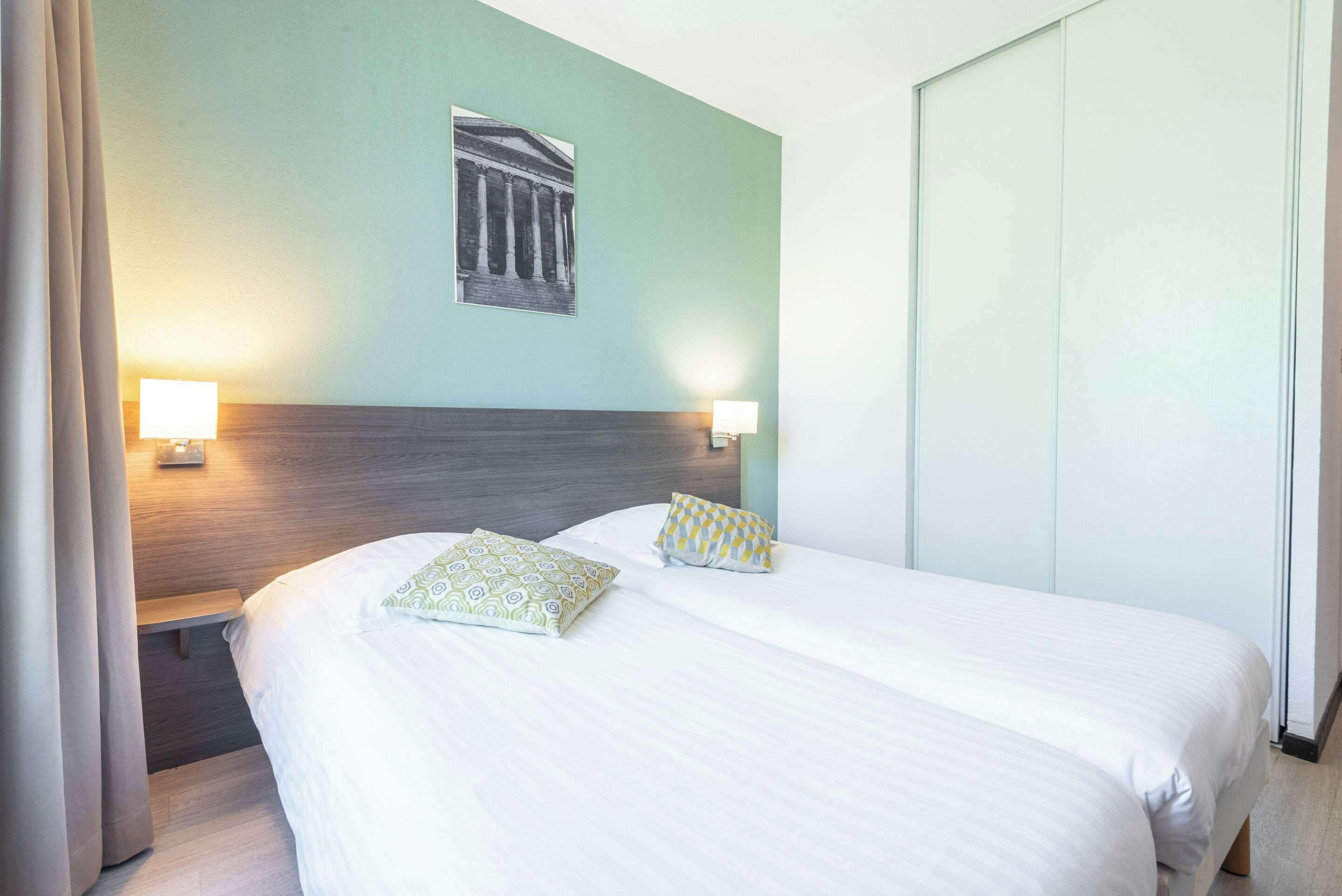 A hotel room with a large bed, two bedside tables with lamps, a headboard, and a wall-mounted picture.