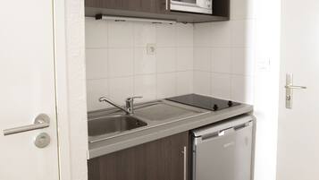 A compact kitchen with a built-in microwave, a sink, and a dishwasher.