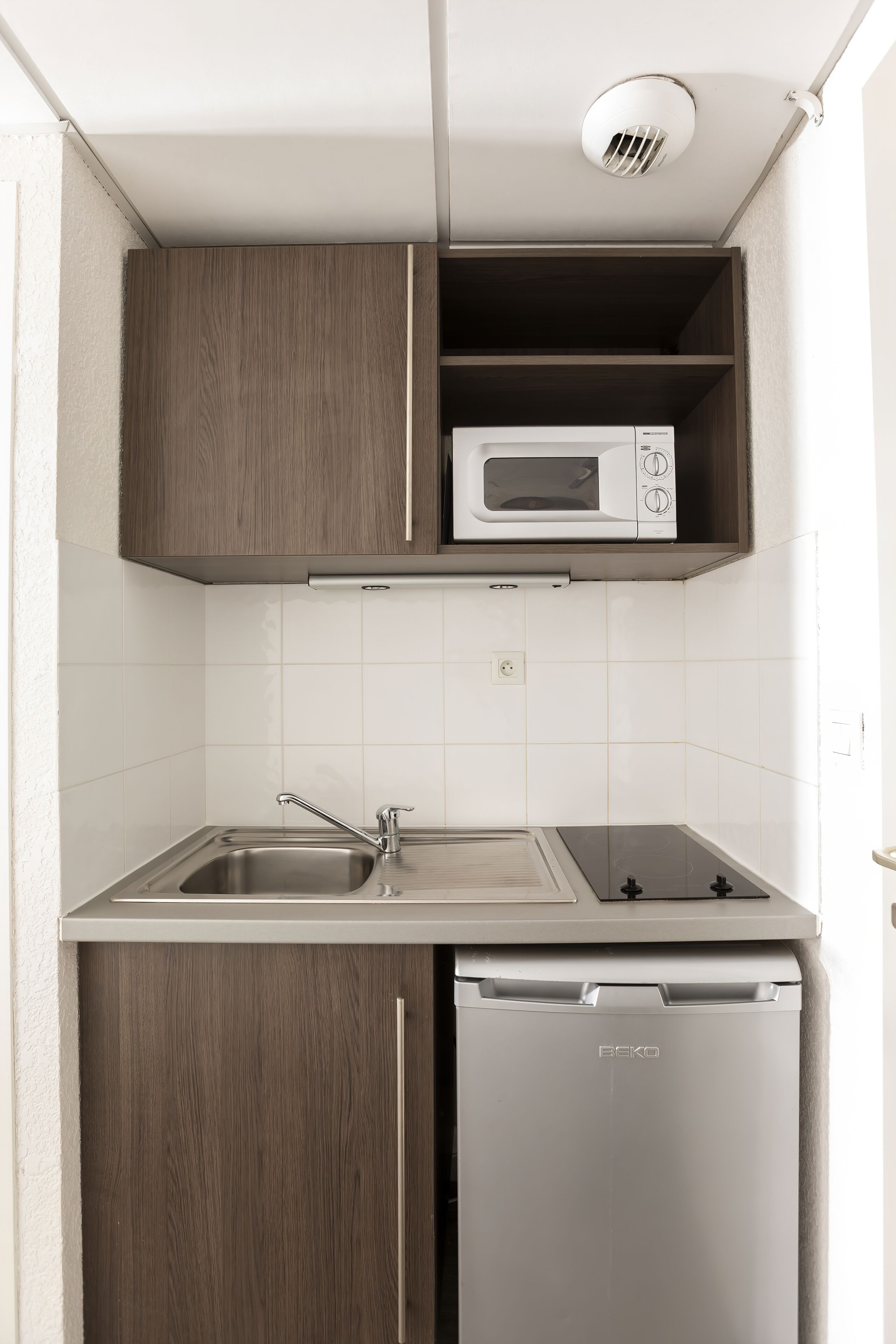 A compact kitchen with a microwave, sink, and dishwasher.
