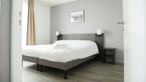 Ein modernes Schlafzimmer mit Bett, Nachttischen und einem Wandbild.