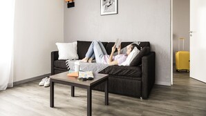 Ein modernes Wohnzimmer mit einem dunklen Sofa, einem Couchtisch und einem gerahmten Bild an der Wand.