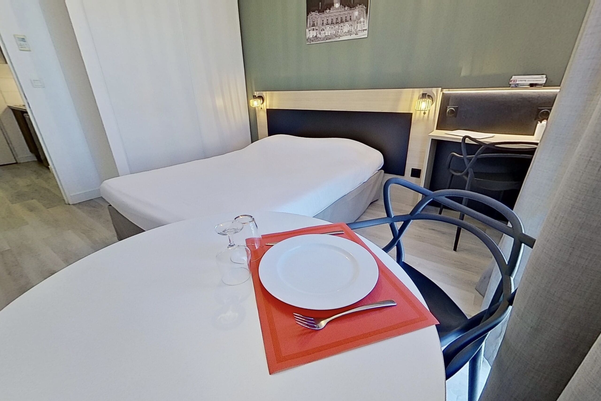 Une chambre d’hôtel avec deux lits simples, une table à manger avec une assiette et une fourchette, et une chaise.