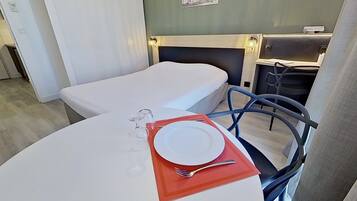Habitación de hotel con dos camas individuales, una mesa de comedor con un plato y un tenedor, y una silla.