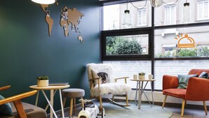 Una habitación acogedora con un ventanal grande, un mapa en la pared, una mecedora, una mesita con una planta y un coche de juguete.