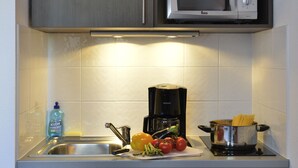 Cocina pequeña equipada con microondas, cafetera y lavavajillas.