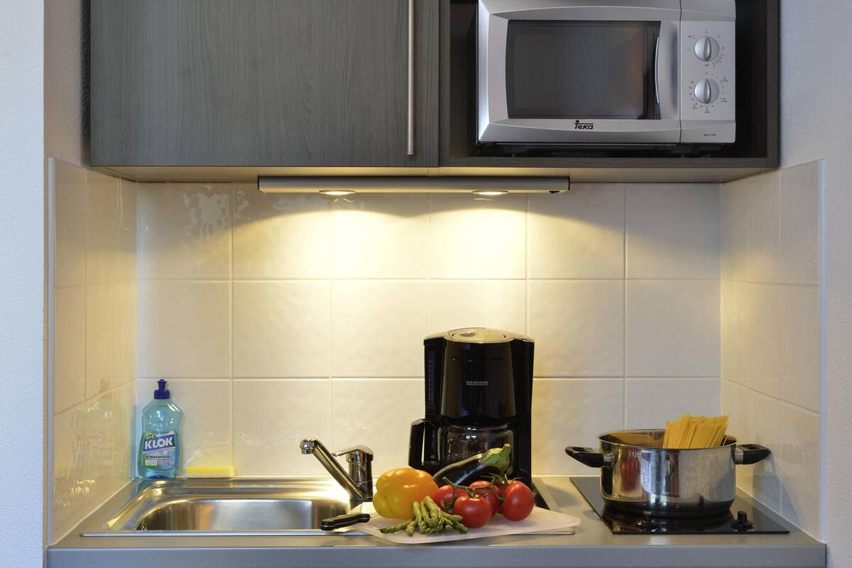Una cocina equipada con microondas, fregadero y estufa.