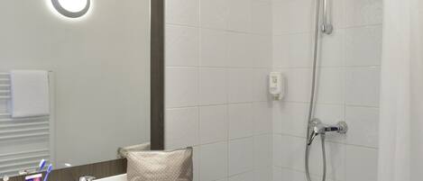Un baño moderno con ducha, lavamanos y espejo.