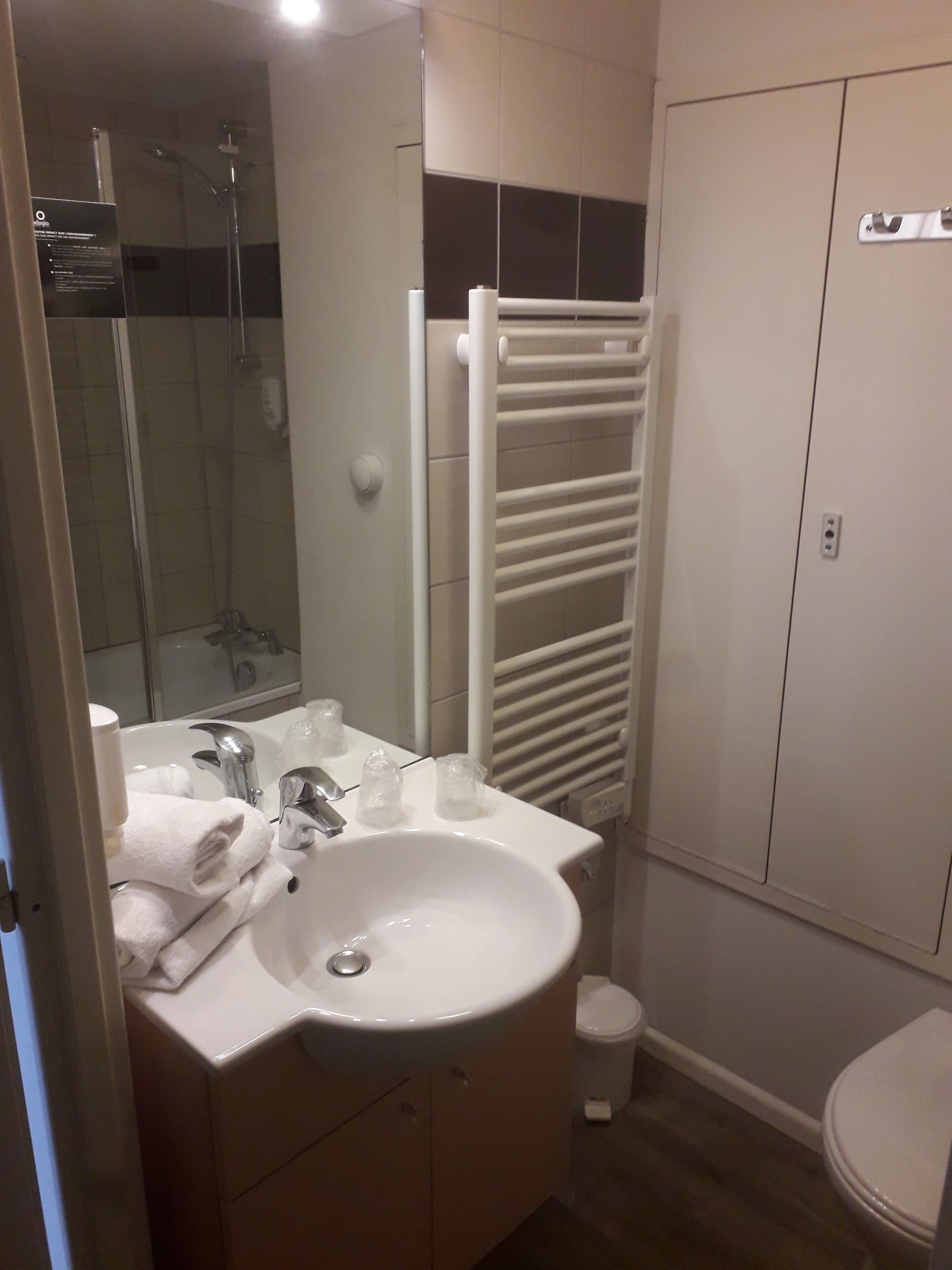 A bathroom with a sink, mirror, towel rack, shower, and toilet.