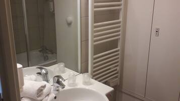 A bathroom with a sink, mirror, towel rack, shower, and toilet.