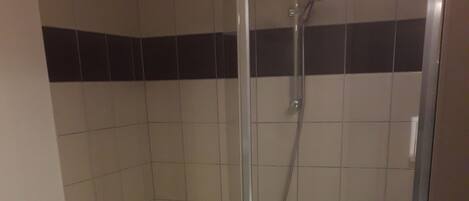 A bathroom with a glass-enclosed shower, a sink with a mirror, and a toilet.