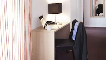 Une chambre d’hôtel équipée d’un bureau, d’une chaise, d’une lampe et d’un miroir mural.