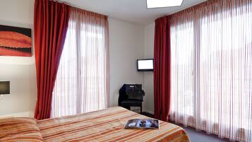 A hotel room with a bed, a television, and a desk with a chair.