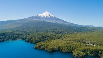 Una montaña con un lago en primer plano y una zona boscosa al fondo.