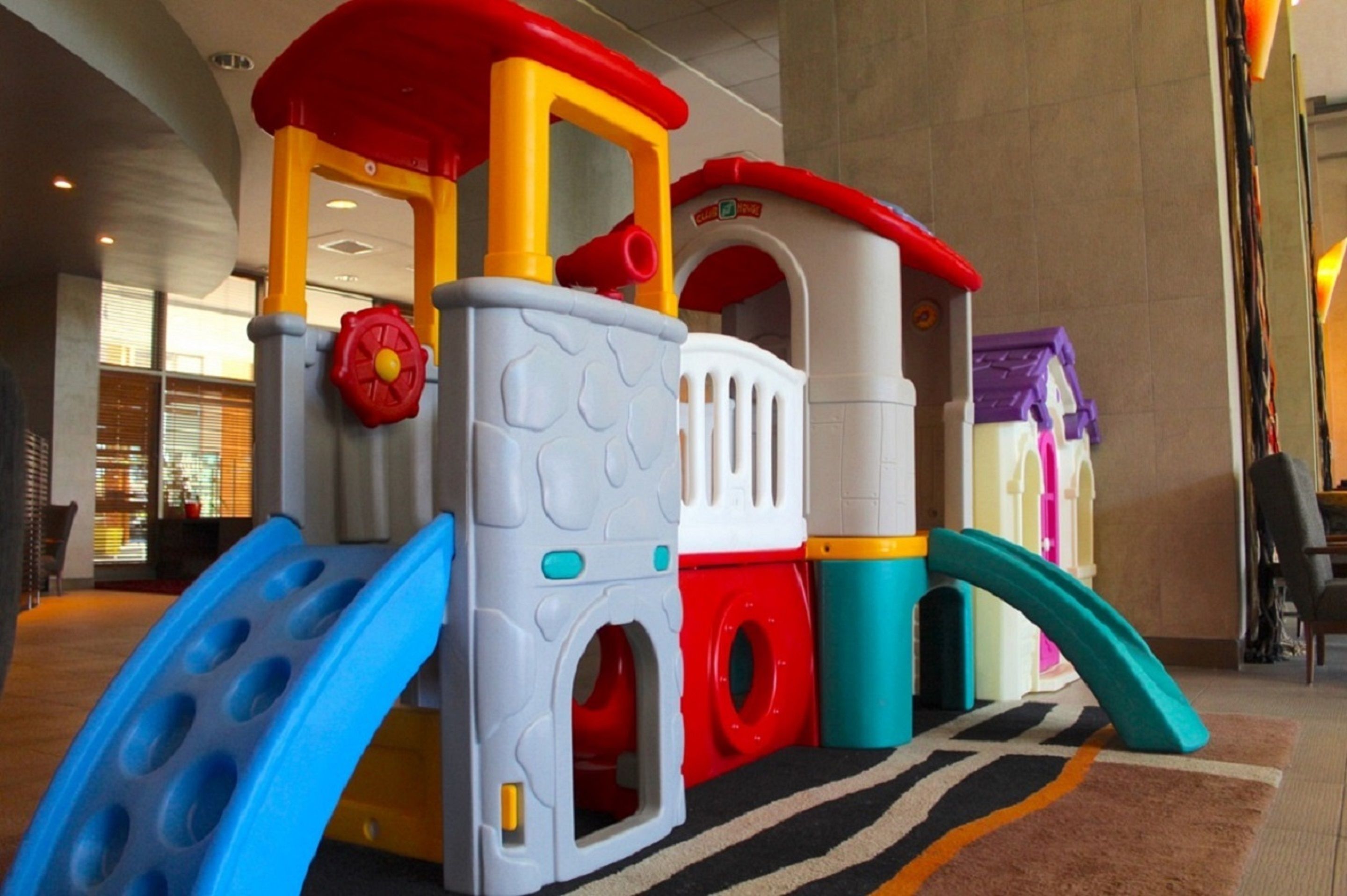 Zona de juegos infantiles con tobogán, estructura para escalar y una casita.