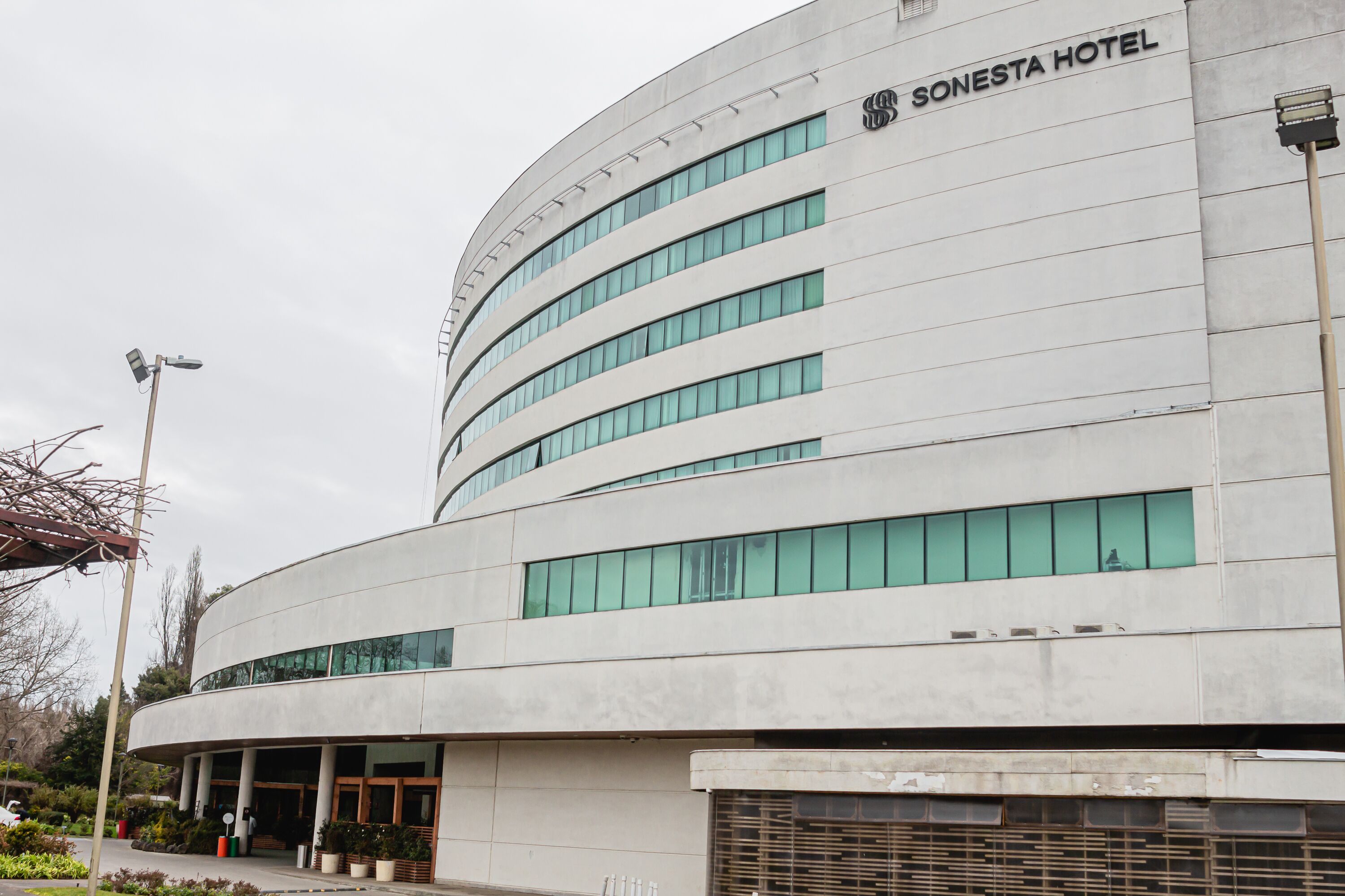 Un moderno edificio de hotel con fachada curva, múltiples ventanas y un cartel que indica que es el Hotel Sonesta.
