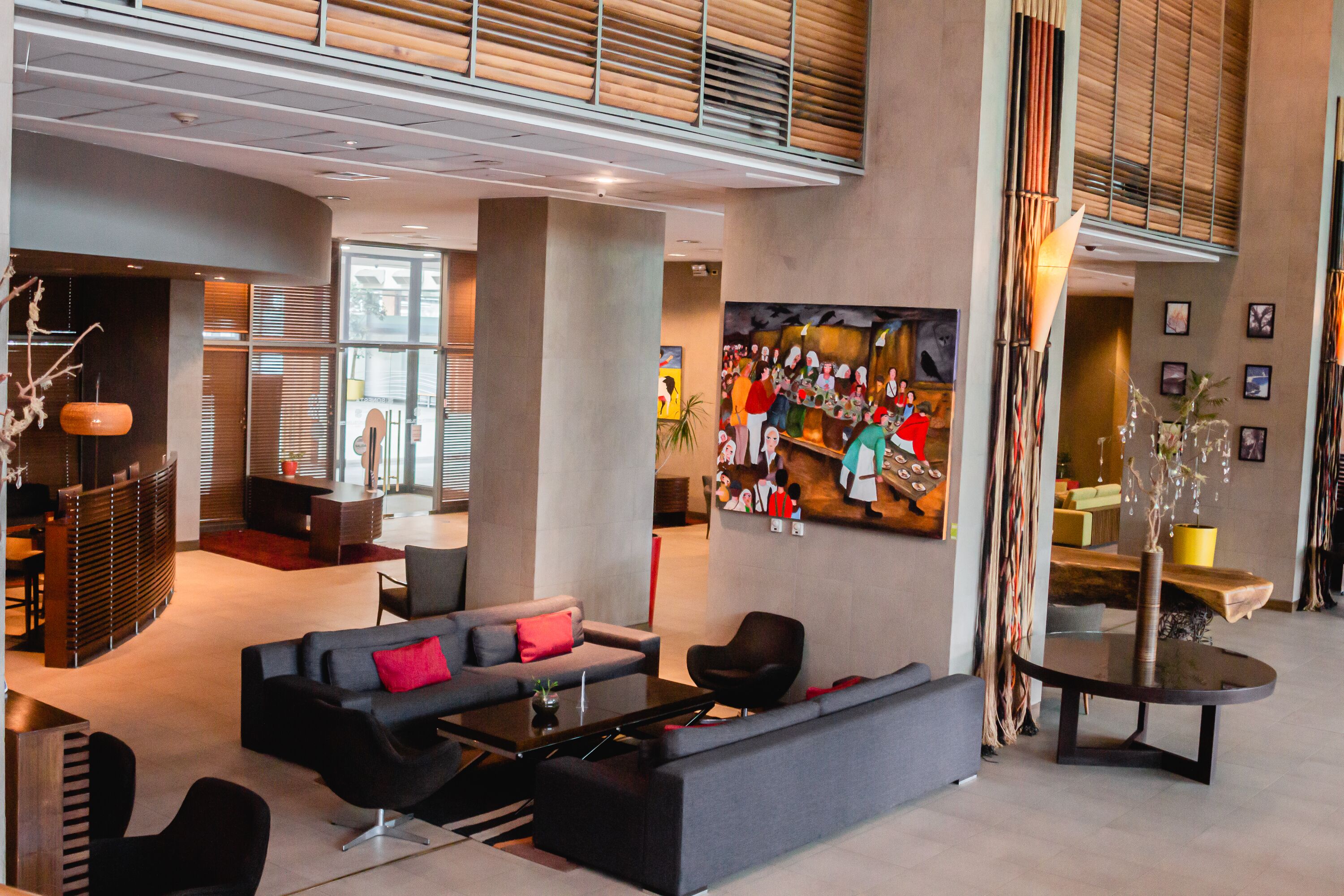 A modern lobby with a sectional sofa, a coffee table, and a large painting on the wall.