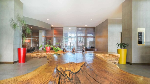 A spacious lobby with a large wooden table, potted plants, and a modern interior design. - Sonesta Hotel Osorno (Osorno)