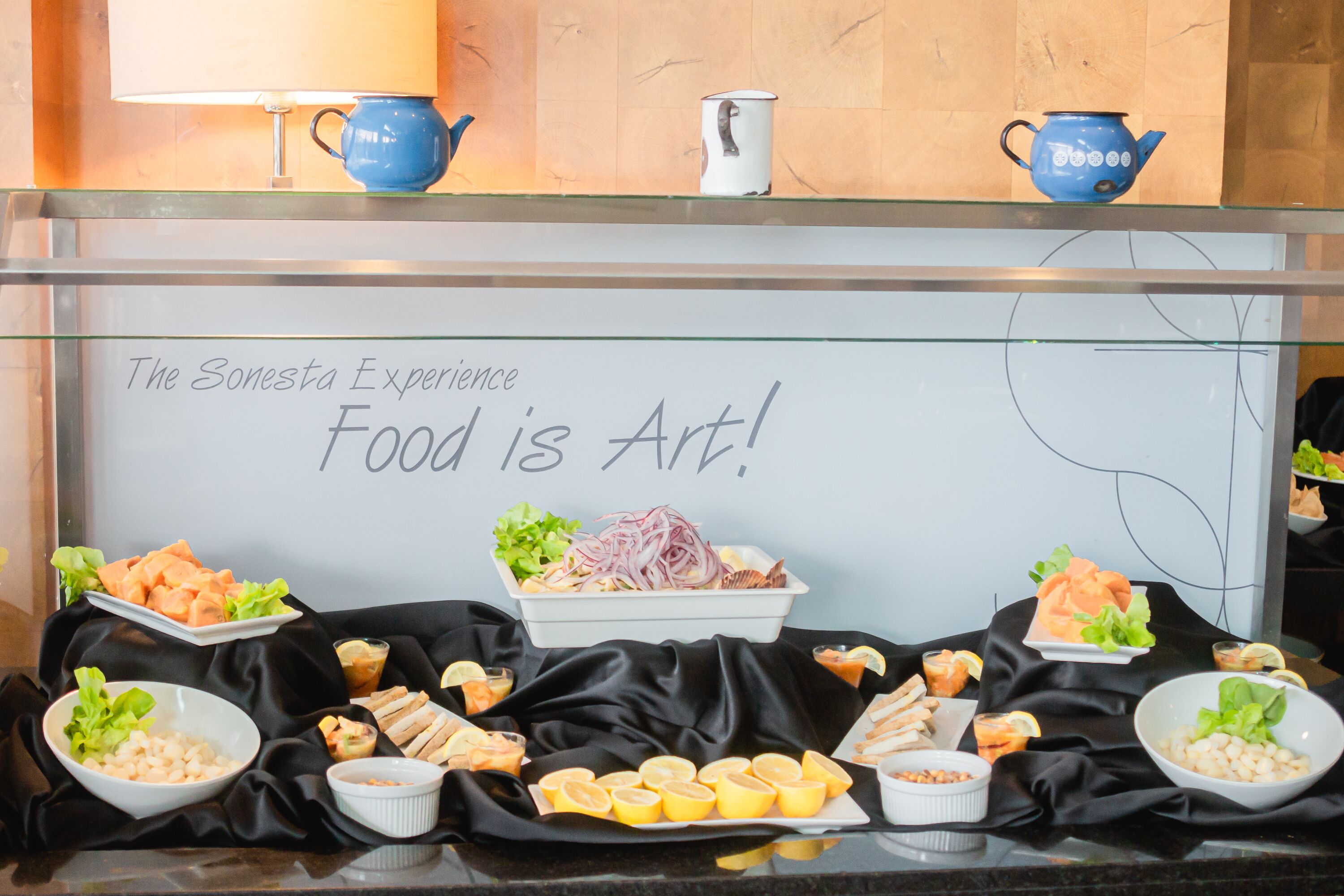 Una mesa de buffet con diversos alimentos y un letrero que dice 'The Sonesta Experience Food is Art!'