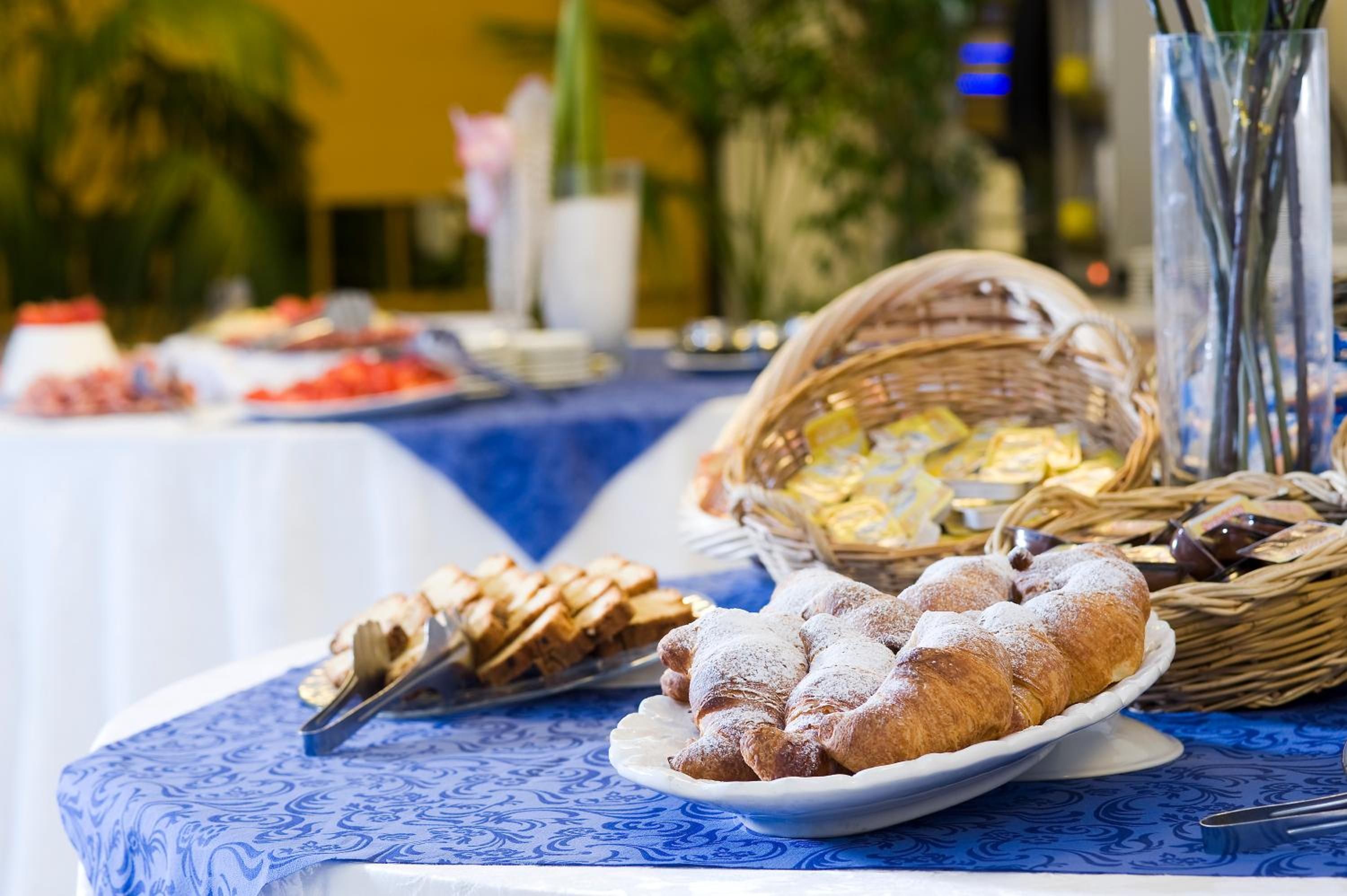 A buffet table with various food items, including pastries and bread, set on a blue tablecloth.