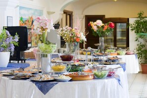 A buffet table with various food items and floral centerpieces. - Park Hotel Terme Mediterraneo (Forio)