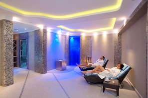 A spa room with two reclining chairs, a small table with a candle, and a wall-mounted heater. - Park Hotel Terme Mediterraneo (Forio)