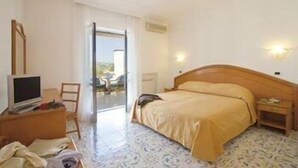 Quarto de hotel com cama, televisão, escrivaninha e cadeira.