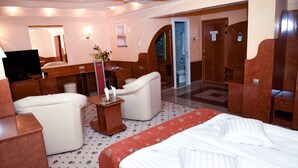 Una habitación de hotel con cama, escritorio, silla, televisión y baño.