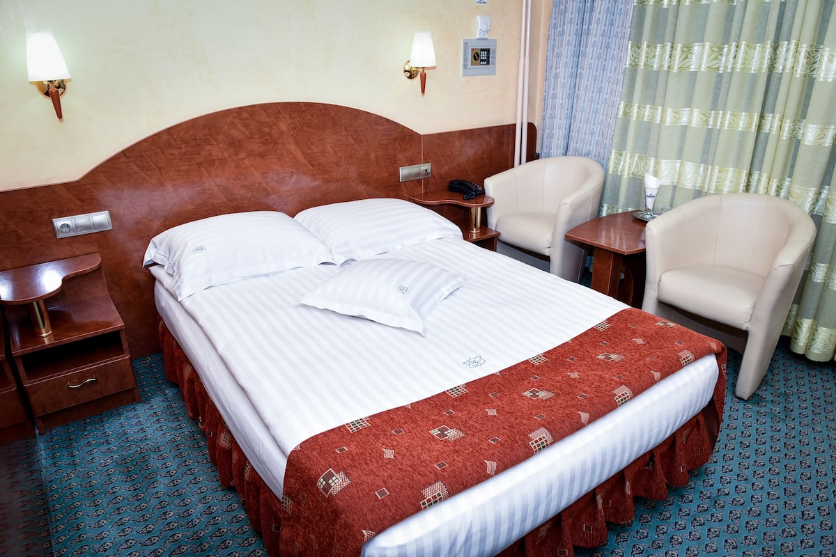Una habitación de hotel con una cama grande, dos mesitas de noche, una silla y un escritorio.