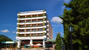 Un hotel de varios pisos con balcones, techo verde y vistas del entorno.