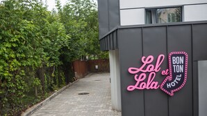 Entrada d'hotel amb un cartell de neó que diu "Lola et Bon Ton Hotel" a la façana d'un edifici modern.