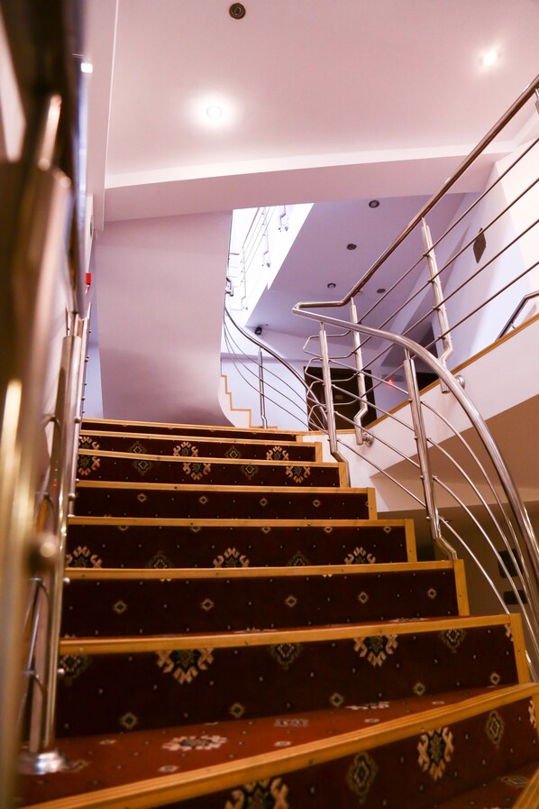 A staircase with a metal railing and patterned steps leading to a landing.