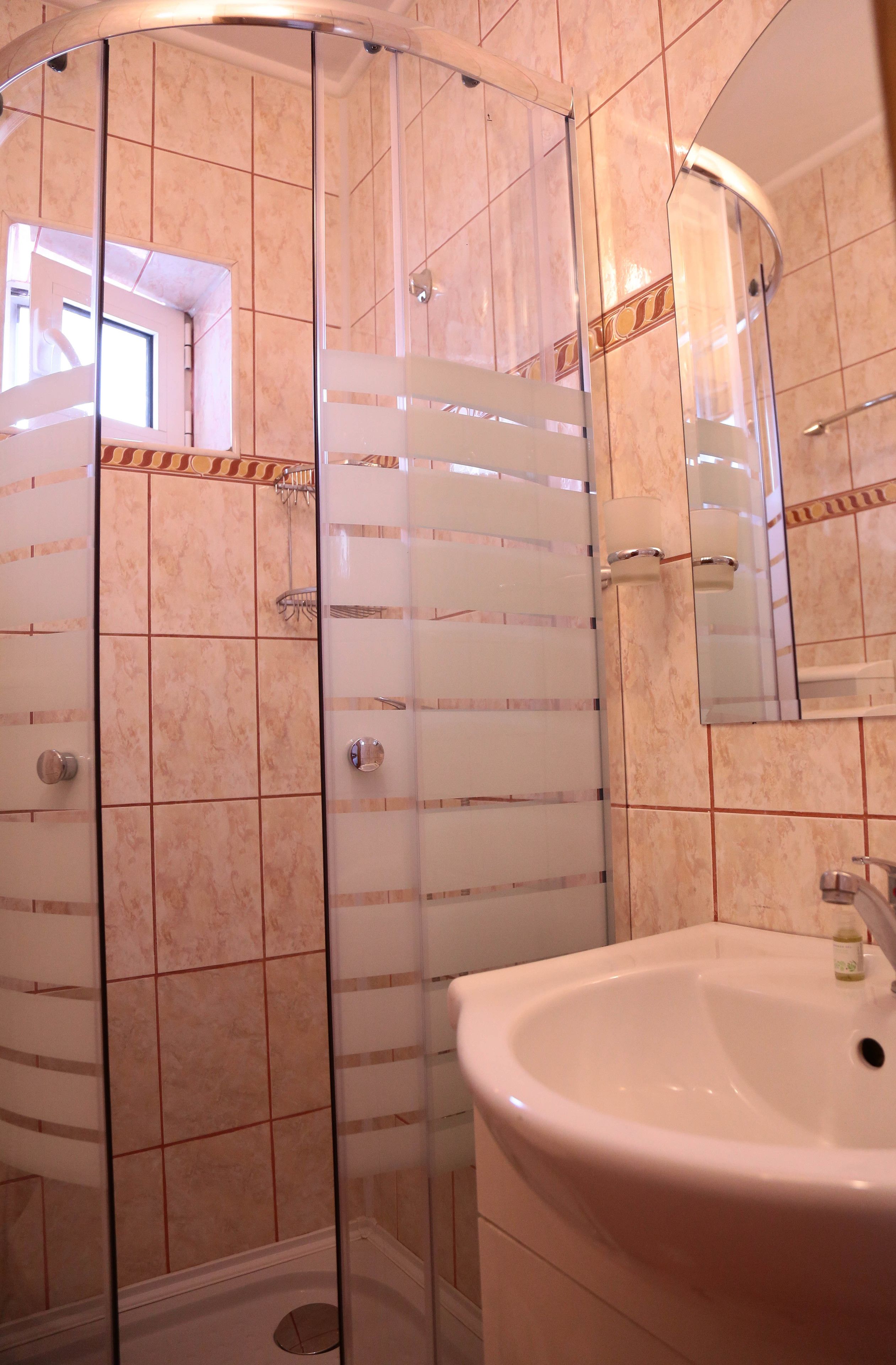 Un baño con ducha de vidrio, lavamanos blanco y espejo.