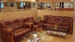 A lobby with two leather sofas, a glass coffee table, and a reception desk. - Hotel Apollonia (Brasov)