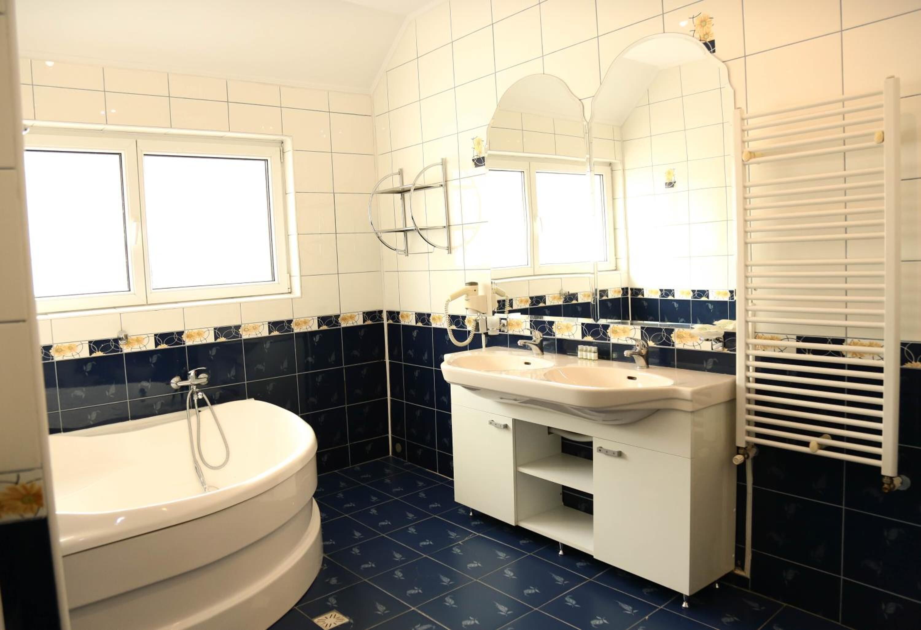 A bathroom with a bathtub, two sinks, a mirror, and a window.