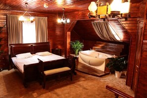 A wooden room with a bed, a bench, a small table, a plant, and a bathtub. - Hotel Apollonia (Brasov)