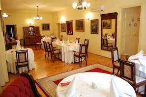 A dining area with round tables, chairs, and a wooden cabinet.