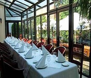 A covered dining area with tables set for a meal, surrounded by chairs.