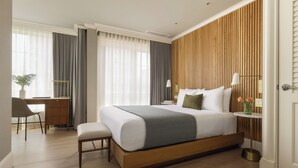 A modern hotel room with a large bed, a desk, and a small table with flowers. - Hotel Veritas (Cambridge)