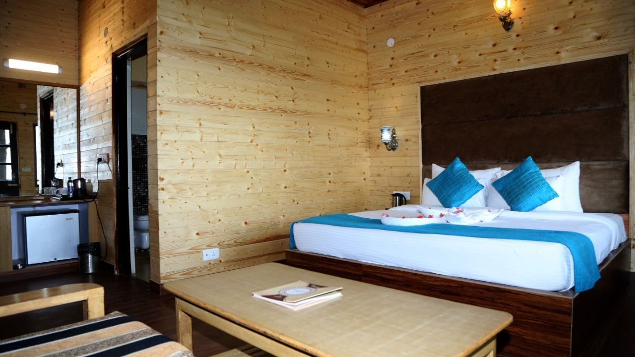 A wooden cabin room with a bed, bedside table, and a small kitchenette.