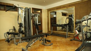 A gym with exercise equipment, a mirrored wall, and a tiled floor. - Winnies (Kasauli)