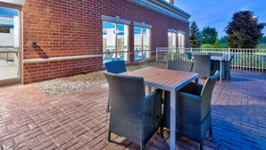 A patio area with wicker furniture and a brick building.