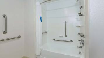 Ein Badezimmer mit Badewanne, Haltegriffen und einer Duschkabine.